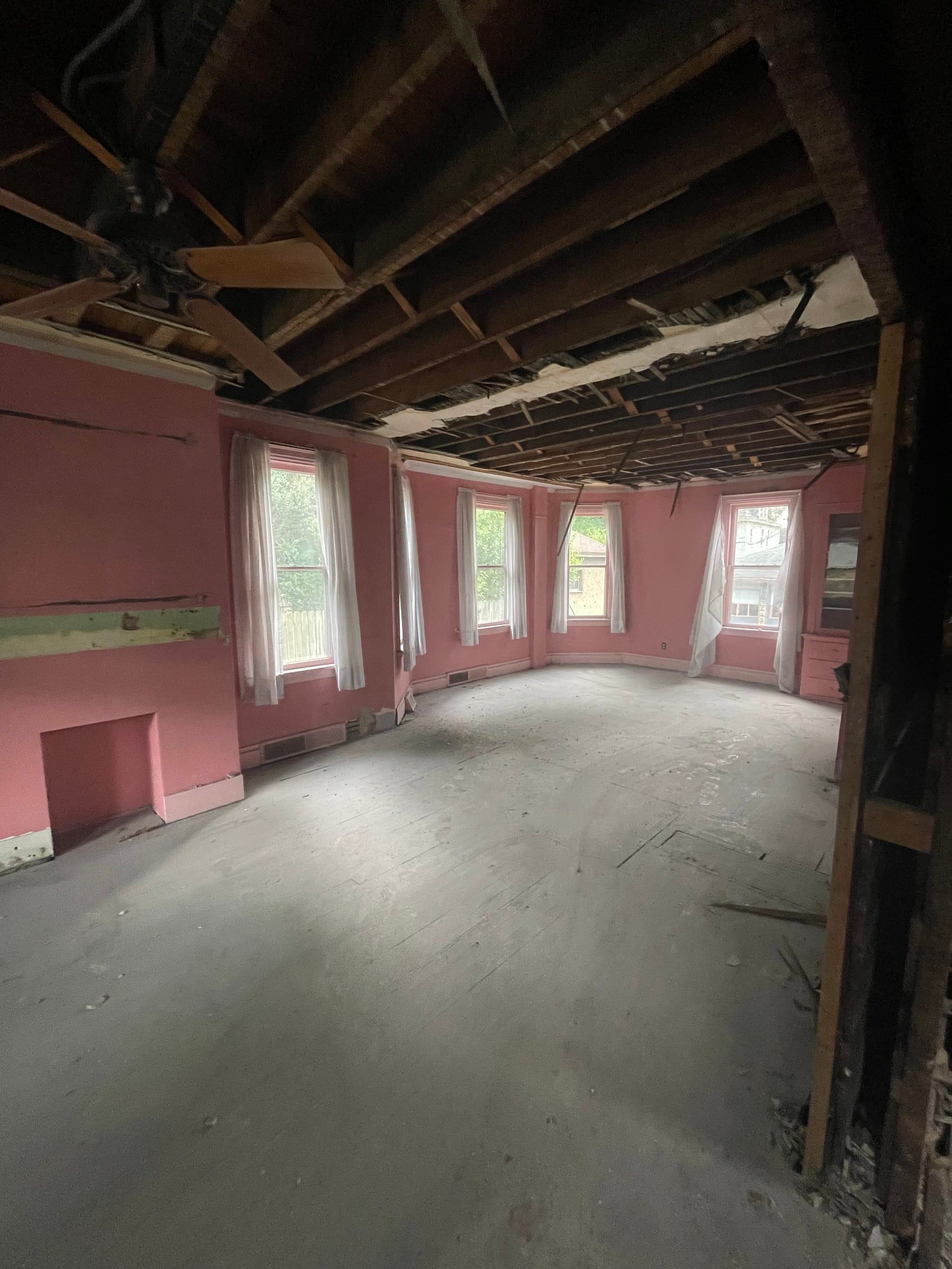 The living room taken down to the studs, the ceiling open to the joists and the pink walls still up