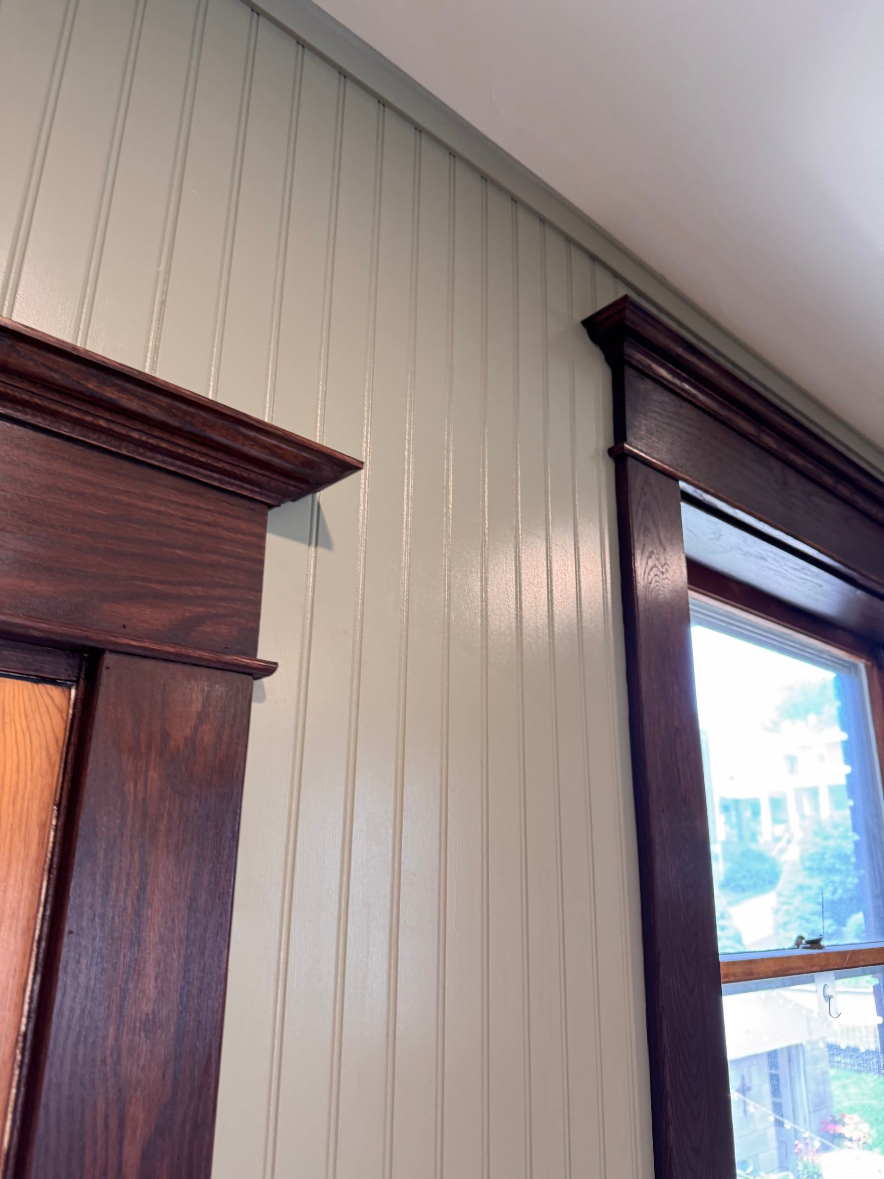 Looking up at a door casing and a window casing side by side, their cornice heads at the same height