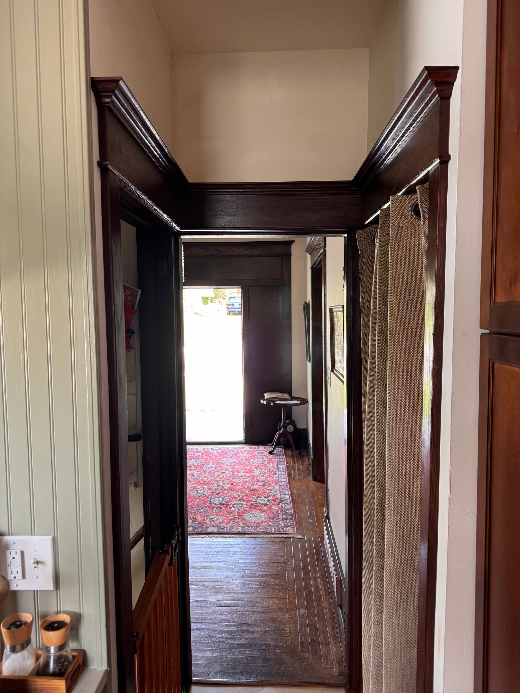 Looking through the connected triple doorway, its stained casings lined up across all three openings, down a hall to the back door