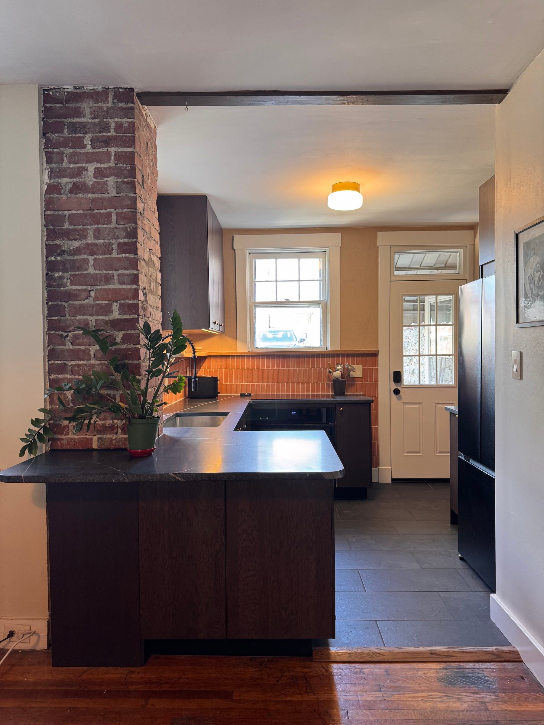The Lawrenceville kitchen: a brick chimney, a dark granite peninsula, and terracotta tile