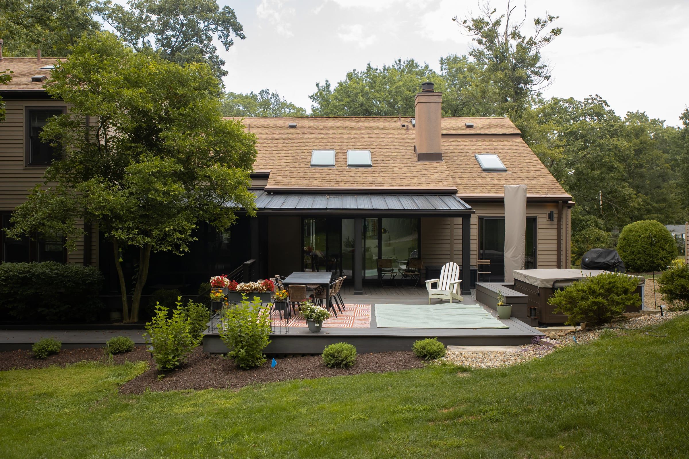 The back of the Moon Township house: a new roof over the screen room, dark composite decking, and the garden