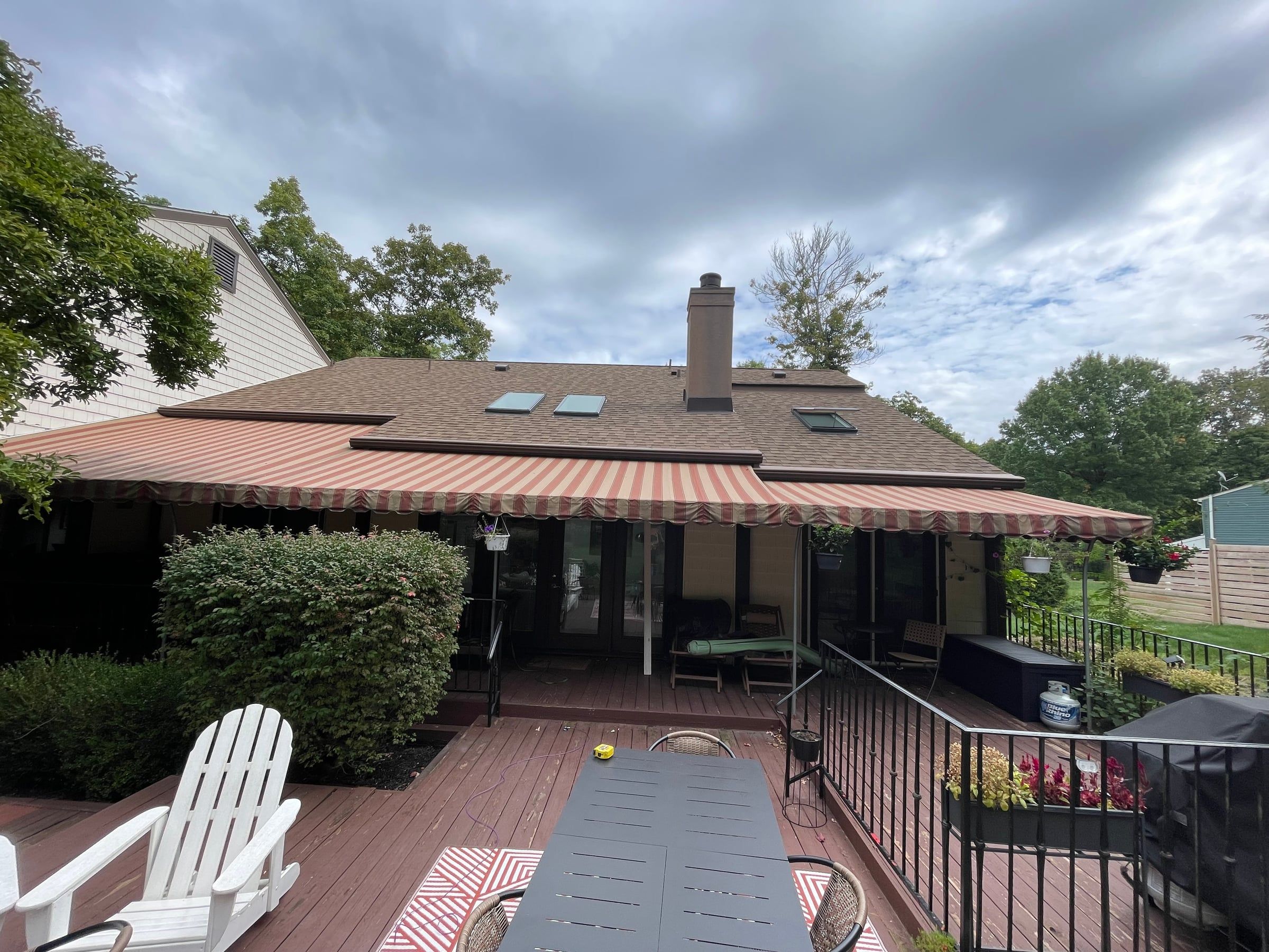The back of the house before: a red-stained wood deck under a faded striped canvas awning