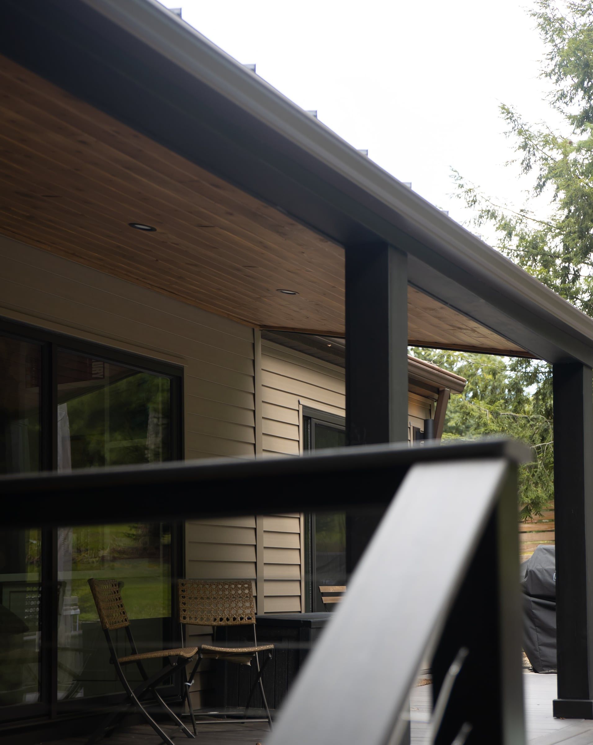 The cedar ceiling under the new roof, with a black railing and sliding doors into the house