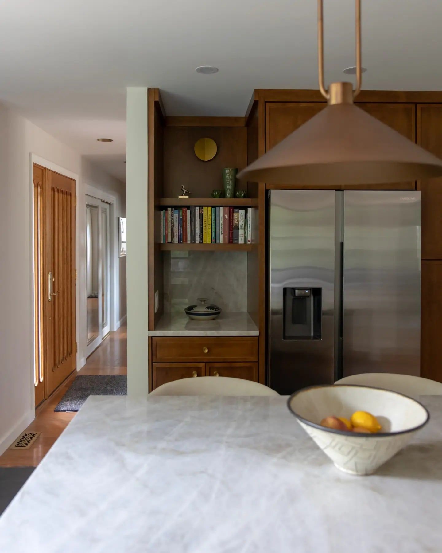 The Moon Township kitchen: warm wood built-ins and a bookshelf, seen past a copper pendant