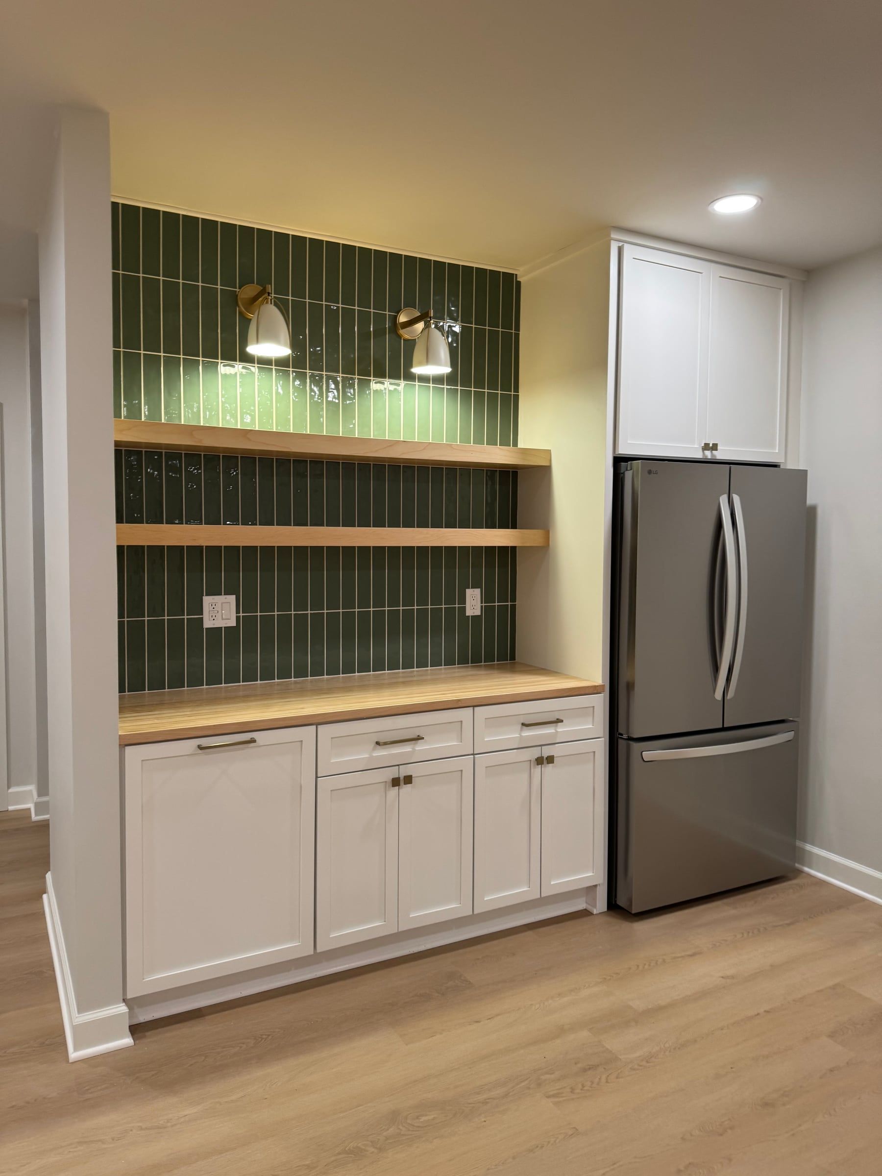 The Wexford basement’s bar: green tile, floating wood shelves, and white cabinets